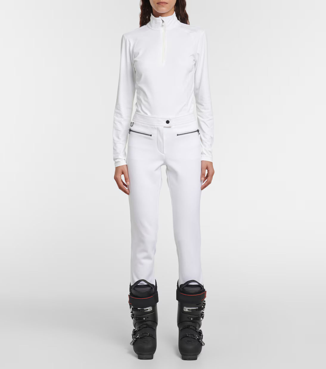 A woman wearing a white Bogner Women's Medita T-Neck sweater that features quick-drying, moisture-wicking, stretchable technical fabric in a slimming, fashionable silhouette.
