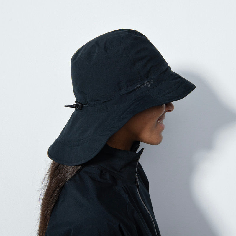 A close-up of a woman wearing a black Daily Sports Flaine Rain Hat that is designed for playing golf in wet and rainy conditions