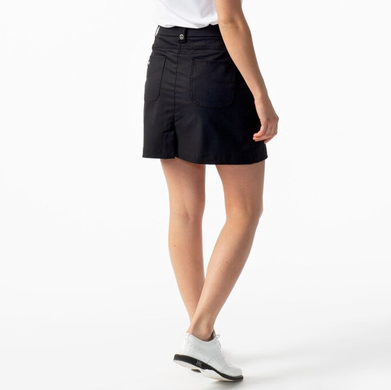 A woman wearing a black Daily Sports Women's Lyric 18" Golf Skort on a white background