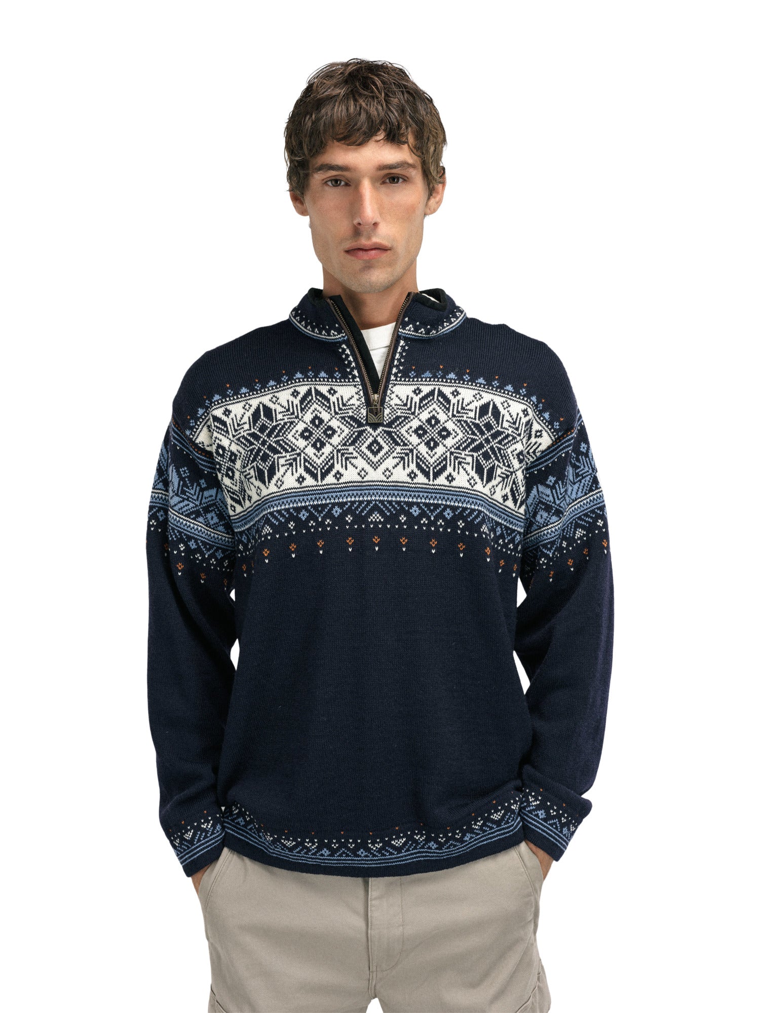A man wearing a navy Dale of Norway Blyfjell Men's Sweater that is made in Norway from luxurious Norweigan merino wool and features a geometric snowflake pattern.