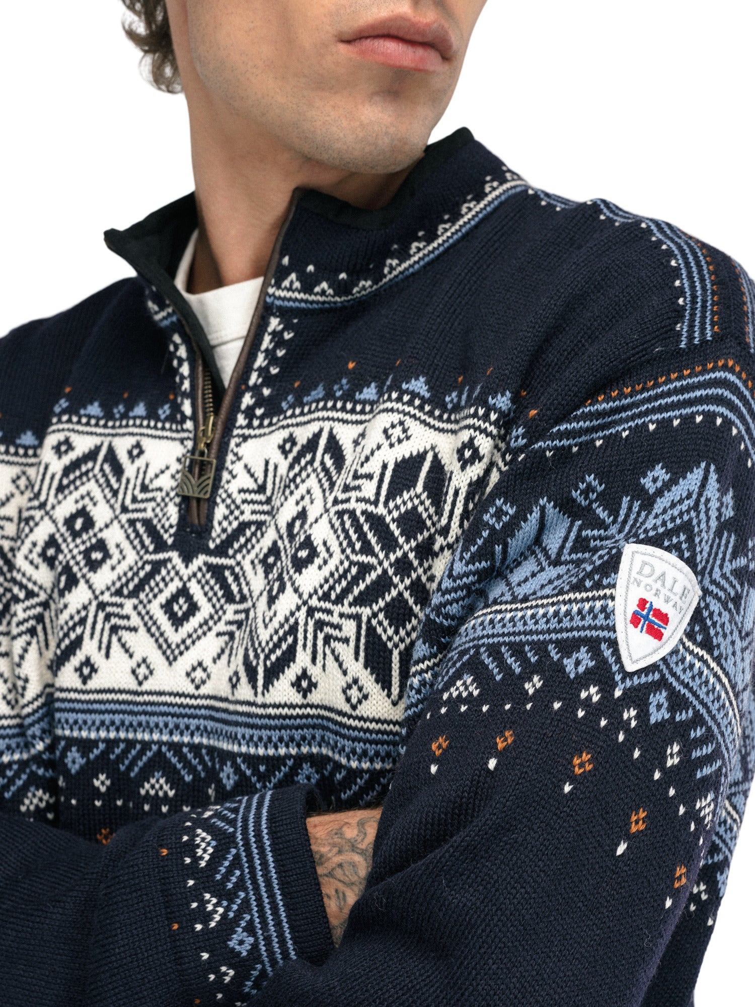 A close-up of a man wearing a navy Dale of Norway Blyfjell Men's Sweater that is made in Norway from luxurious Norweigan merino wool and features a geometric snowflake pattern.