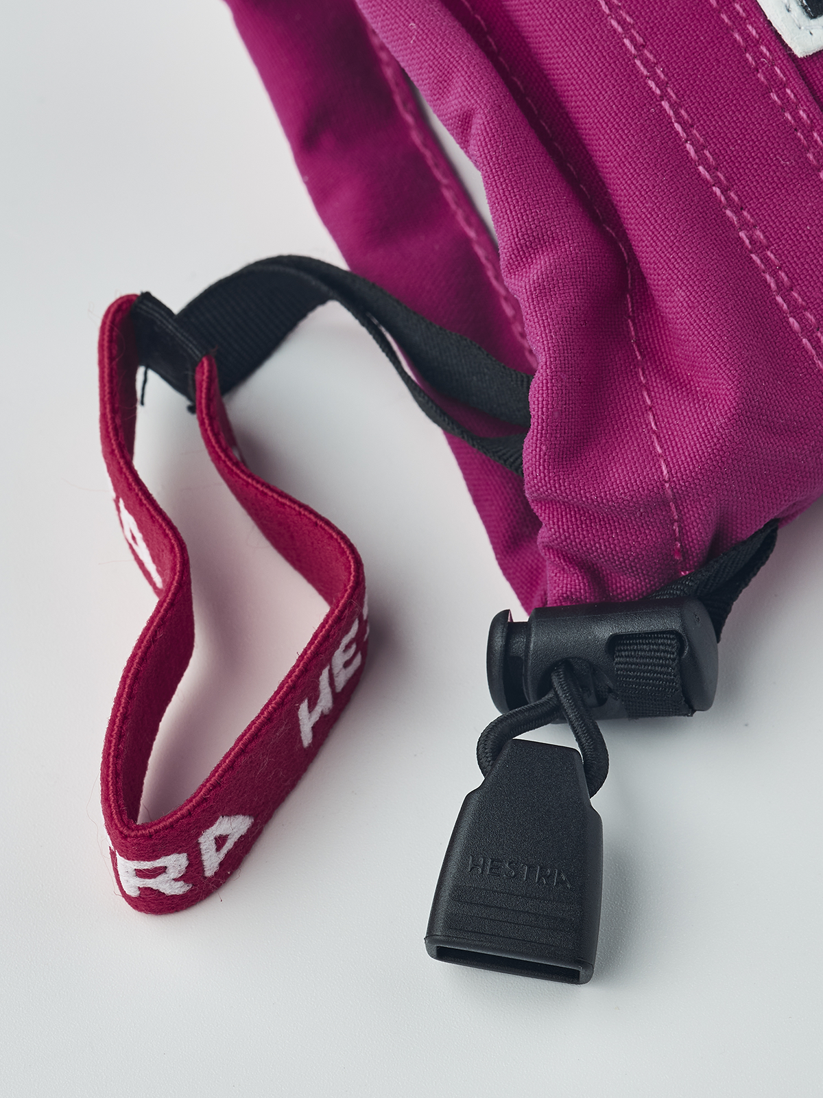 A close-up of the wrist of a pink and white Hestra Junior Army Leather Heli Ski Glove that is made with premium leather.