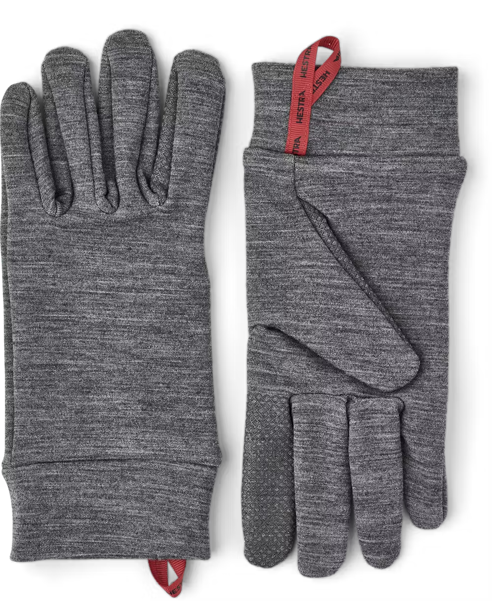 A pair of grey Hestra Touch Point Warmth Glove Liners, which are designed to keep your hands extra warm in freezing conditions.