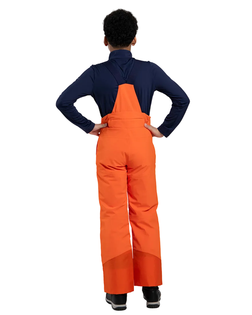 Rear view of orange Kjus Jr Boys’ Vector Max Pants featuring 2-layer waterproof fabric, Fast Thermo Core insulation, water-repellent zippers, reinforced scuff guards, and the KJUS-GROW leg extension system.