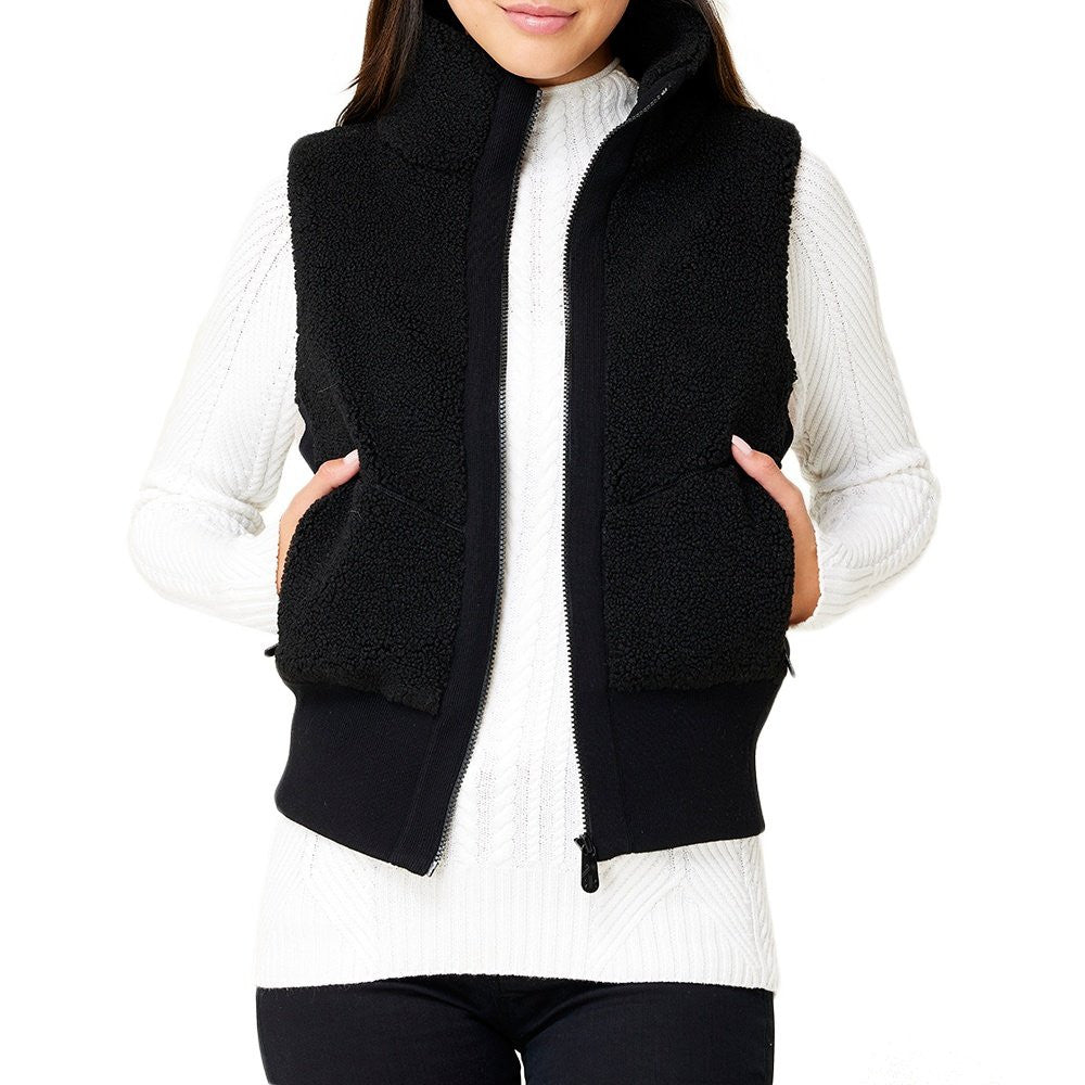 A woman wearing a black Krimson Klover Women's Ember Vest, designed to elevate winter outfits.