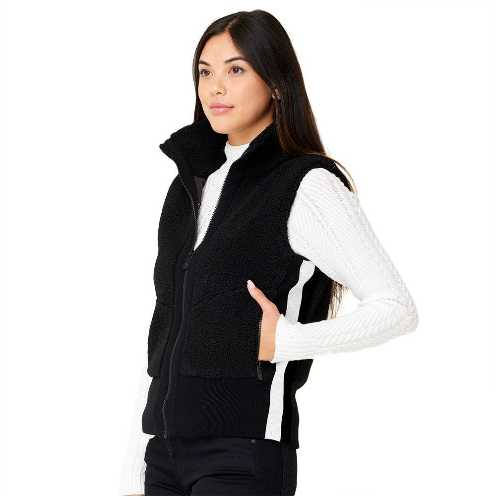 A woman wearing a black Krimson Klover Women's Ember Vest, designed to elevate winter outfits.
