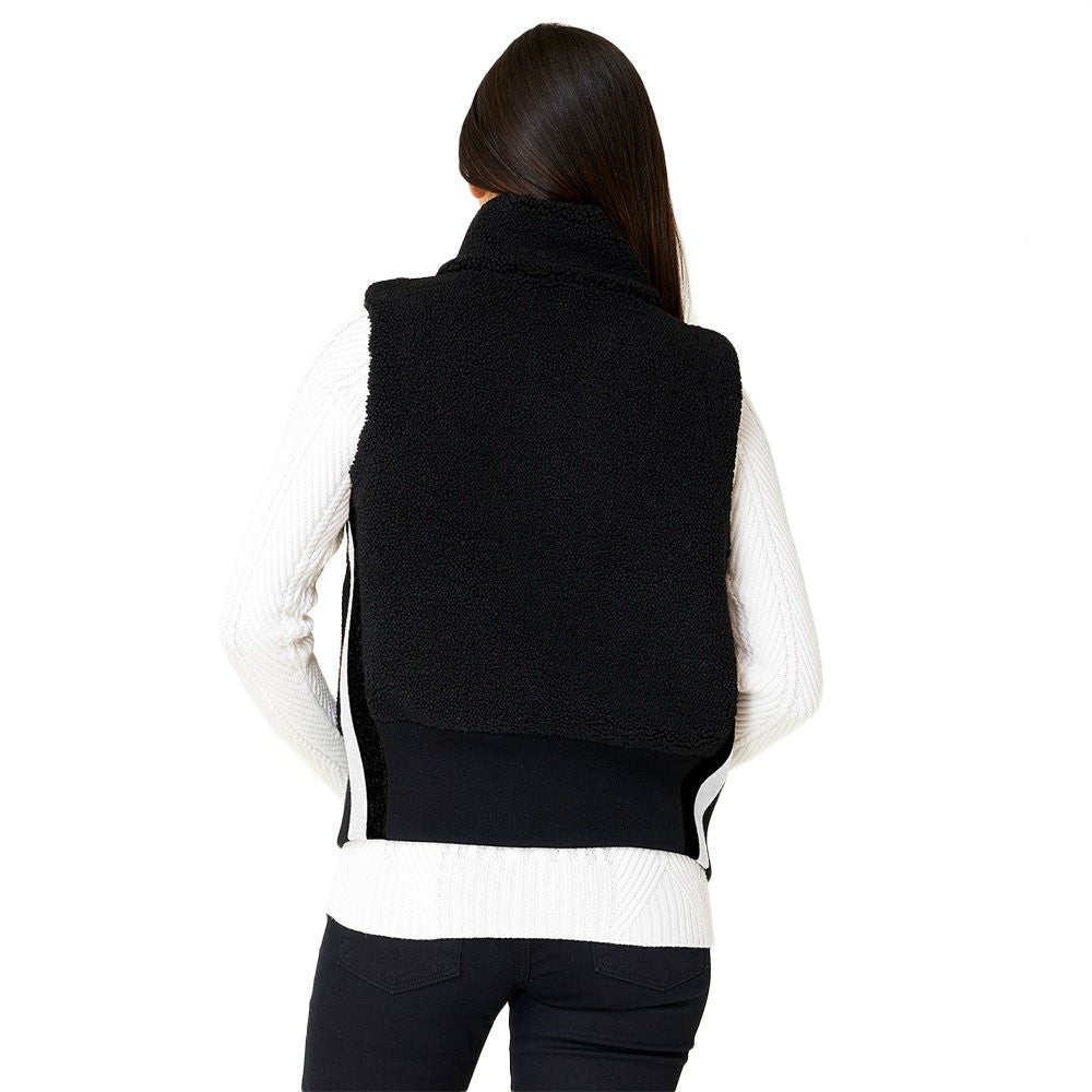 A woman wearing a black Krimson Klover Women's Ember Vest, designed to elevate winter outfits.
