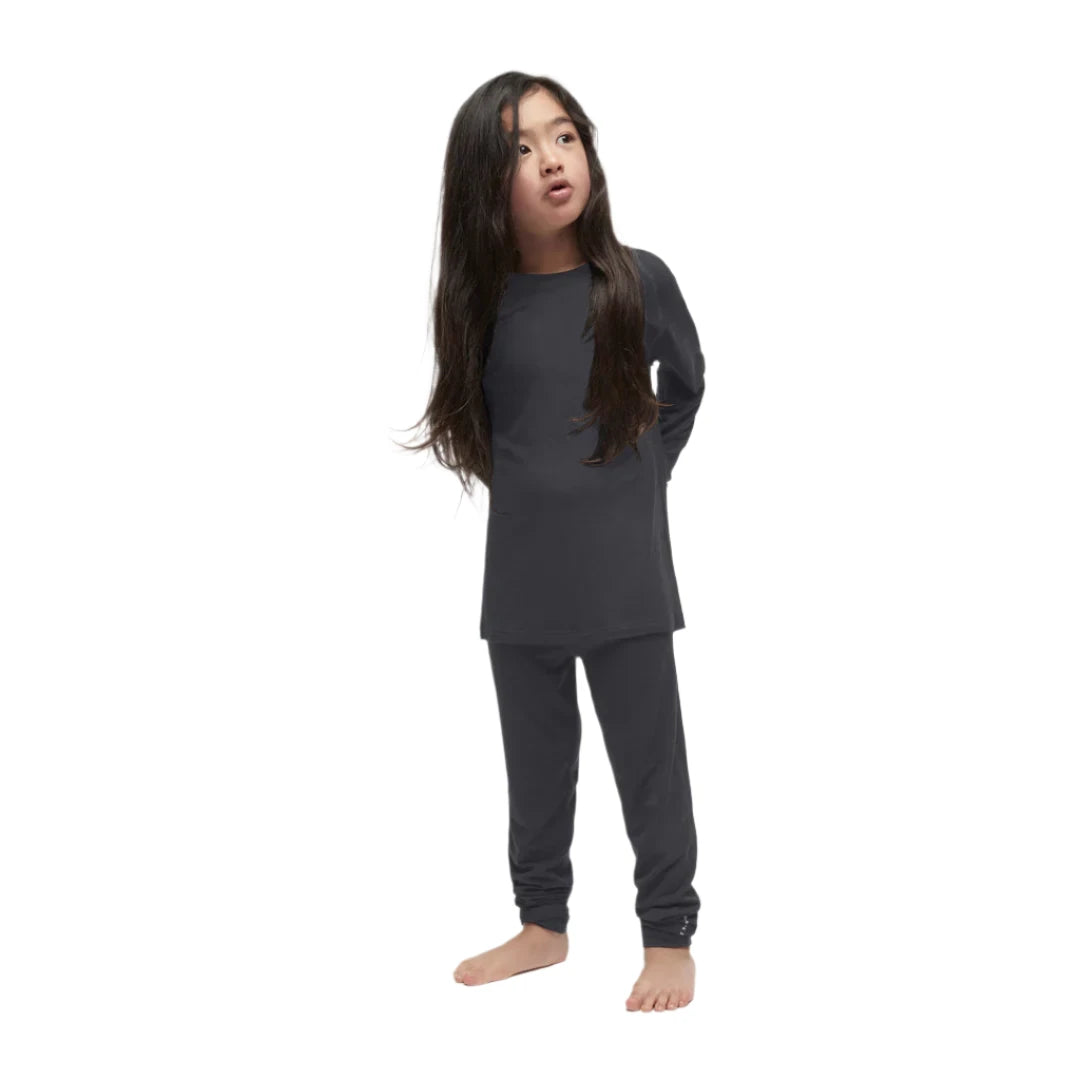 A child wearing a black Le Bent Kids' Core Midweight Raglan Crew Baselayer Top that is stretchable, breathable, and made from a premium bamboo and merino wool blend.