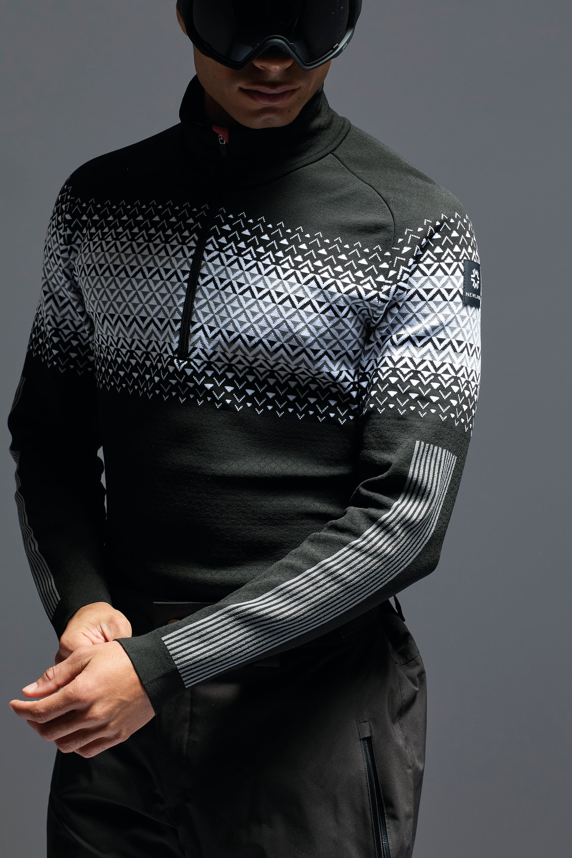 A man wearing a black and white Newland Men's Beaver Creek 1/2 Zip Turtleneck midlayer sweater that is moisture-wicking, breathable, and stretchable.