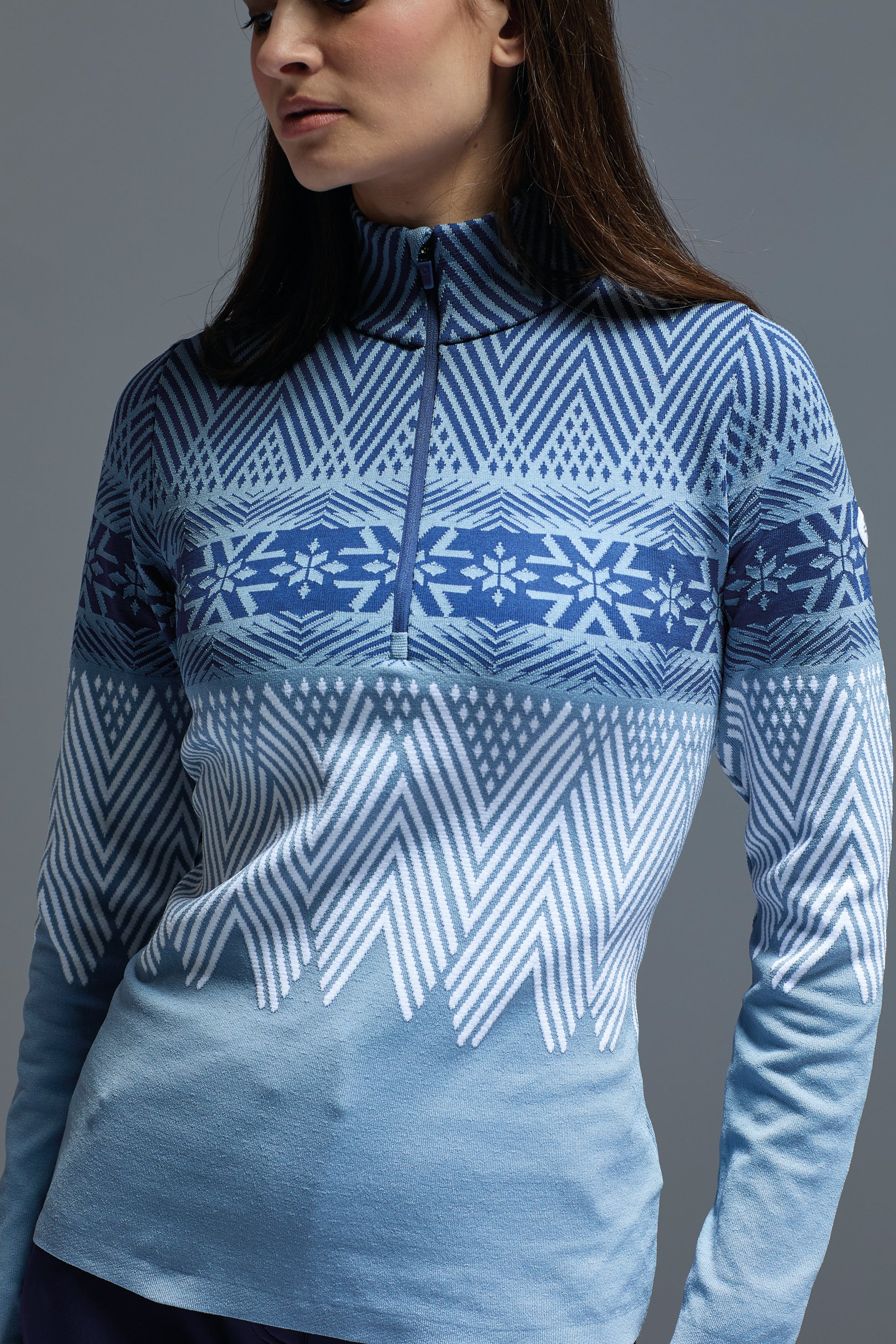A woman wearing a blue Newland Women's Are 1/2 Zip midlayer sweater that is moisture-wicking, breathable, and stretchable.