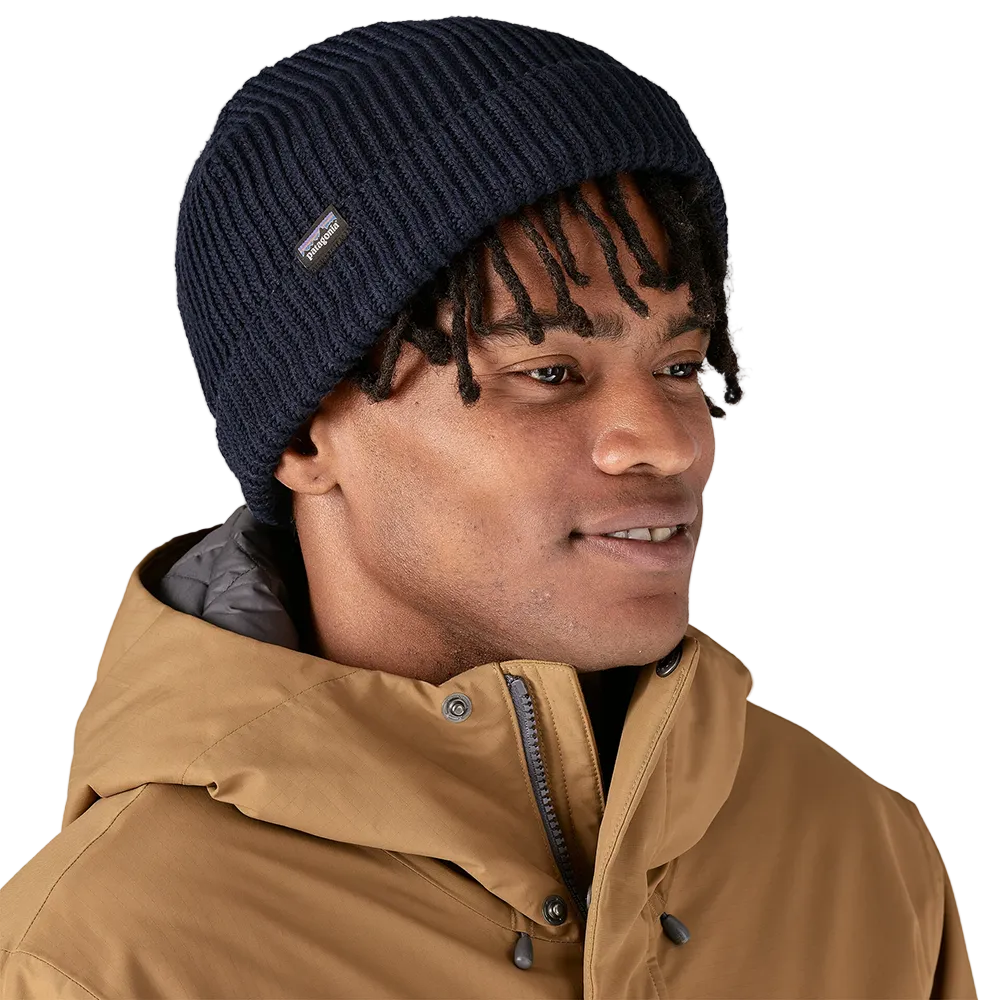 Front view of a navy blue Patagonia Fisherman's Rolled Beanie featuring 100% recycled polyester 1x1 rib-knit construction, an adjustable roll-up cuff, and a woven logo label.