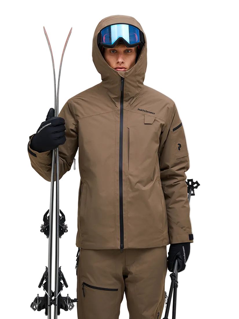 Front view of a tan Peak Performance Men's Alpine GORE-TEX 2L Insulated Shell Jacket featuring a 2-layer GORE-TEX waterproof membrane, YKK AquaGuard storm zippers, a radio pocket, and a helmet-compatible hood.