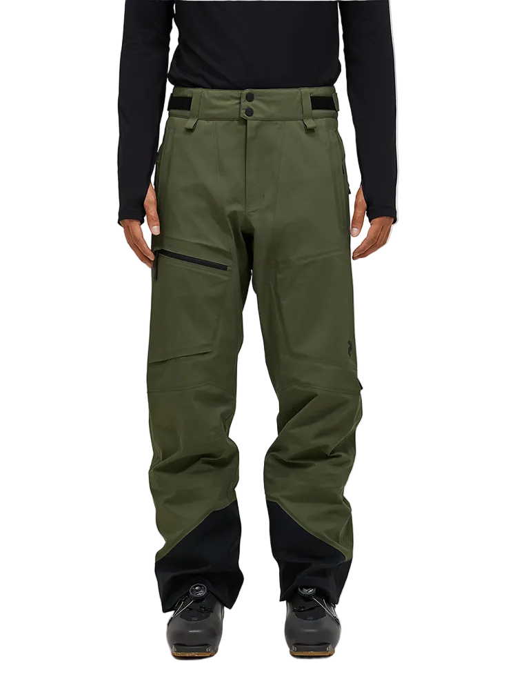 Front view of the pine needle green Peak Performance Men's GORE-TEX C-Knit 3L Shell Pants featuring 3-layer GORE-TEX fabric with C-KNIT backer technology, YKK AquaGuard leg ventilation zips, an adjustable velcro waistband, and reinforced Cordura lower leg scuff guards.