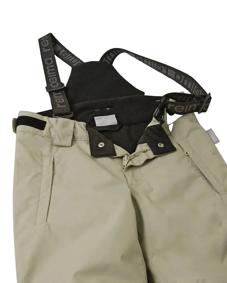 Close-up view of beige Reima Jr Wingon Pants featuring a waterproof Reimatec shell, detachable elastic suspenders, reinforced knee and hem panels, and zippered hand pockets.