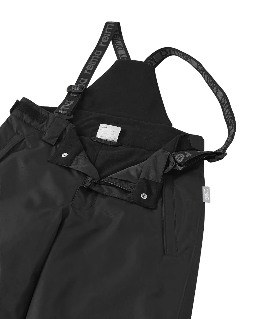Close-up of black Reima Jr Wingon Pants featuring a waterproof Reimatec shell, detachable elastic suspenders, reinforced knee and hem panels, and zippered hand pockets.