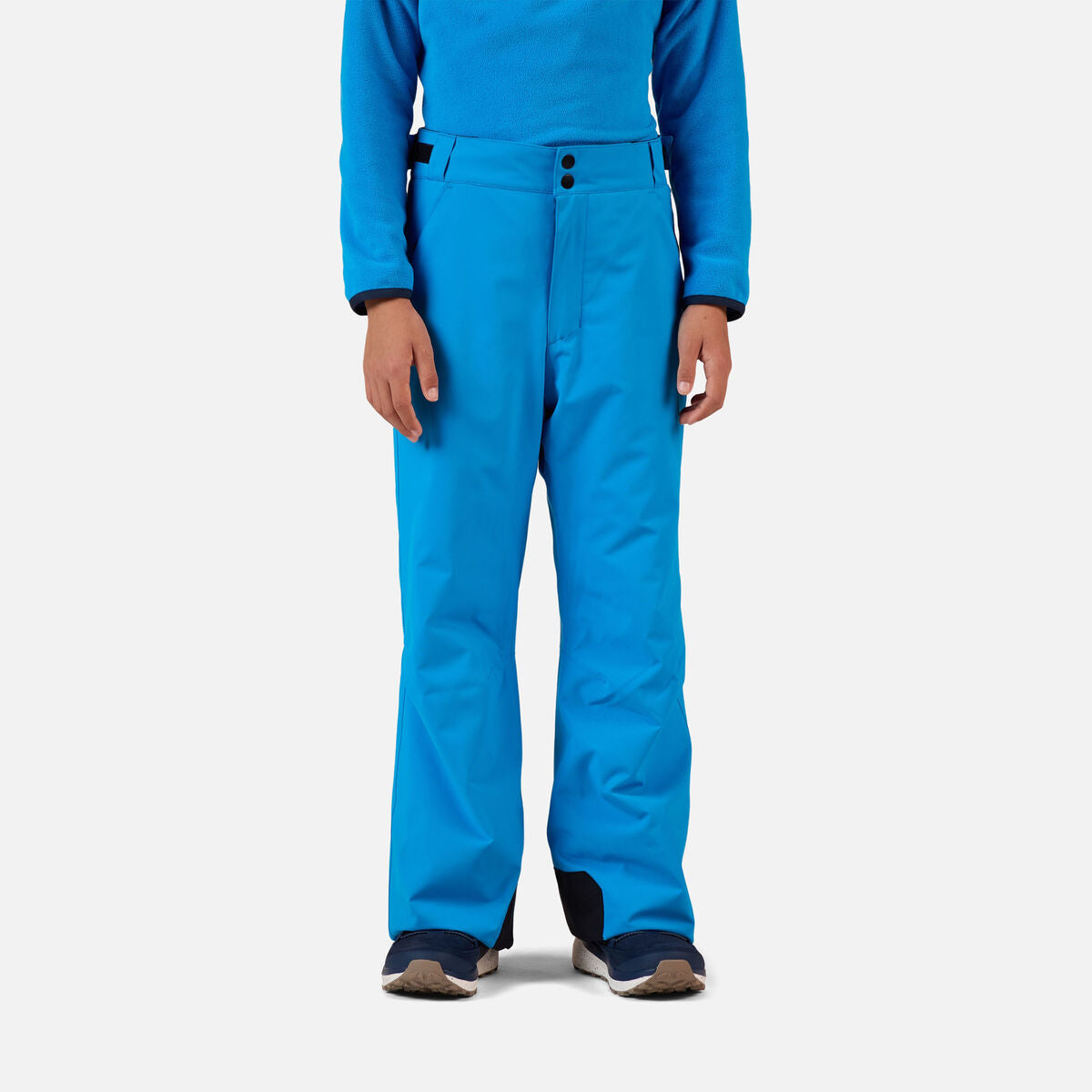 A boy wearing a pair of blue Rossignol Boys' Insulated Ski Pants that are waterproof, breathable, and stretchable.