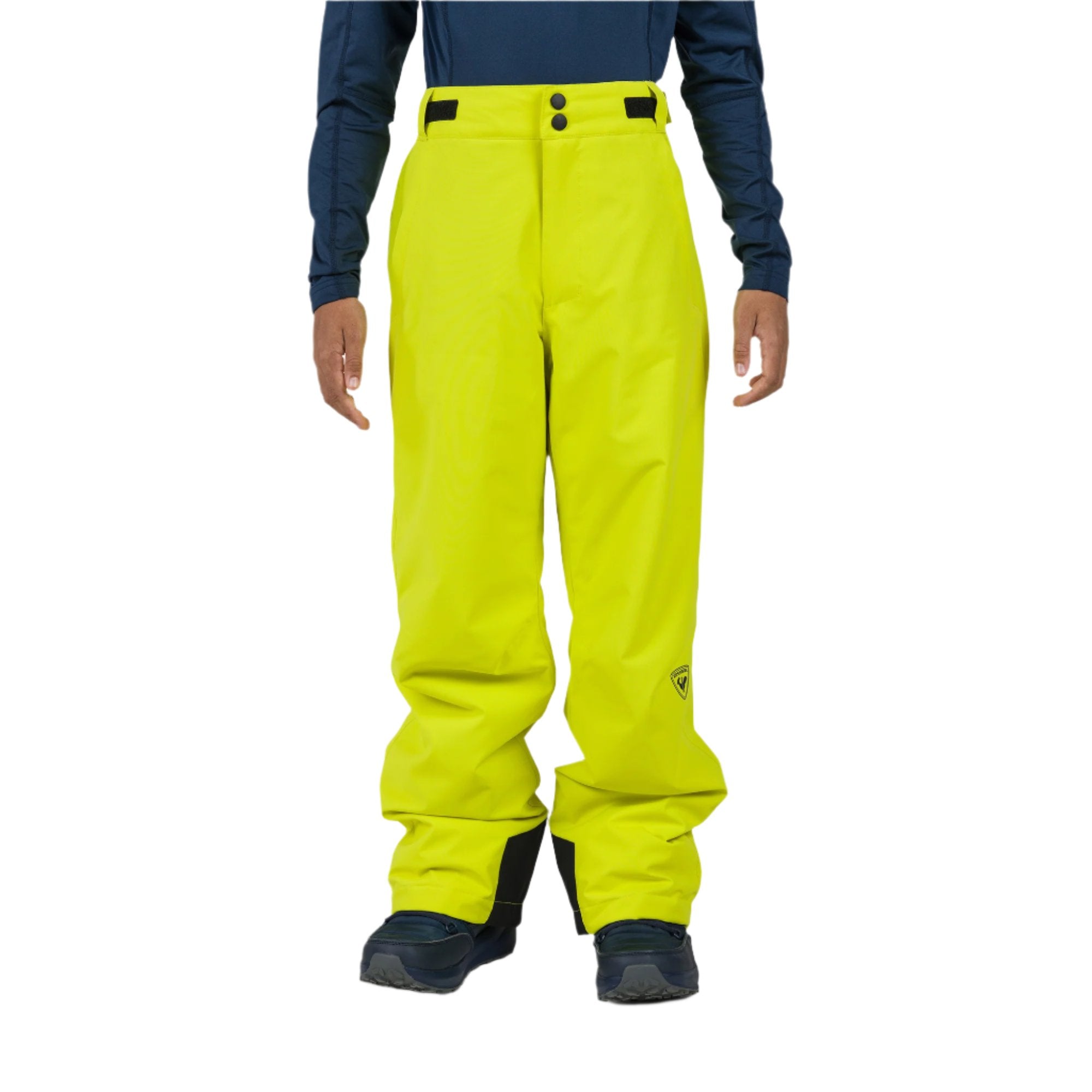 A boy wearing a pair of neon green Rossignol Boys' Ski Pants that are waterproof, breathable, stretchable, and insulated.