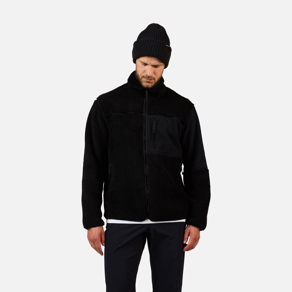 A man wearing a black Rossignol Men's All Track Snap Sherpa Jacket that is moisture-wicking, quickdrying, and warm.