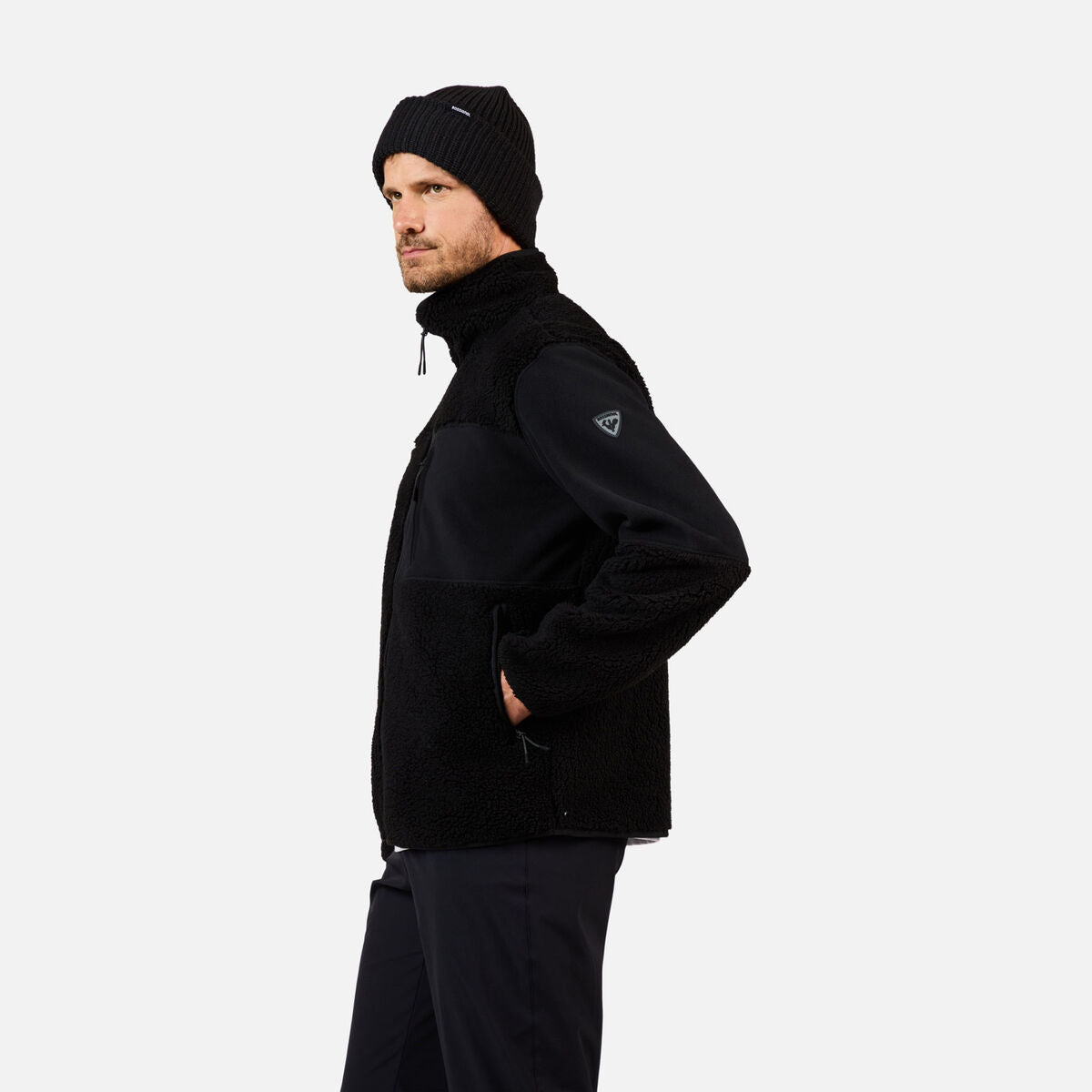 A man wearing a black Rossignol Men's All Track Snap Sherpa Jacket that is moisture-wicking, quickdrying, and warm.