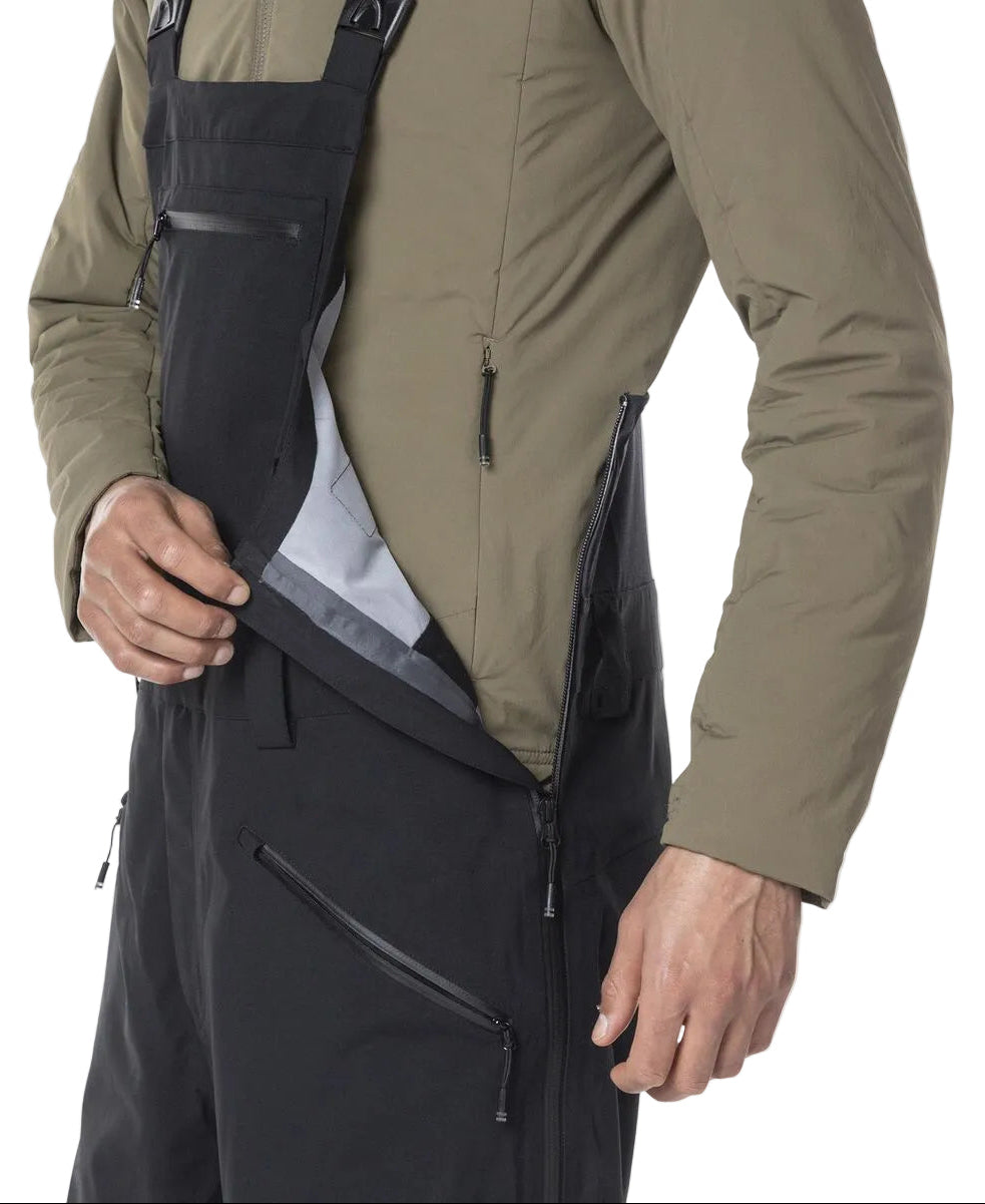 A close-up of a man wearing a pair of black Rossignol Men's SKPR 3L AYR Bib Pants that are waterproof, breathable, stretchable, warm, and include vents.