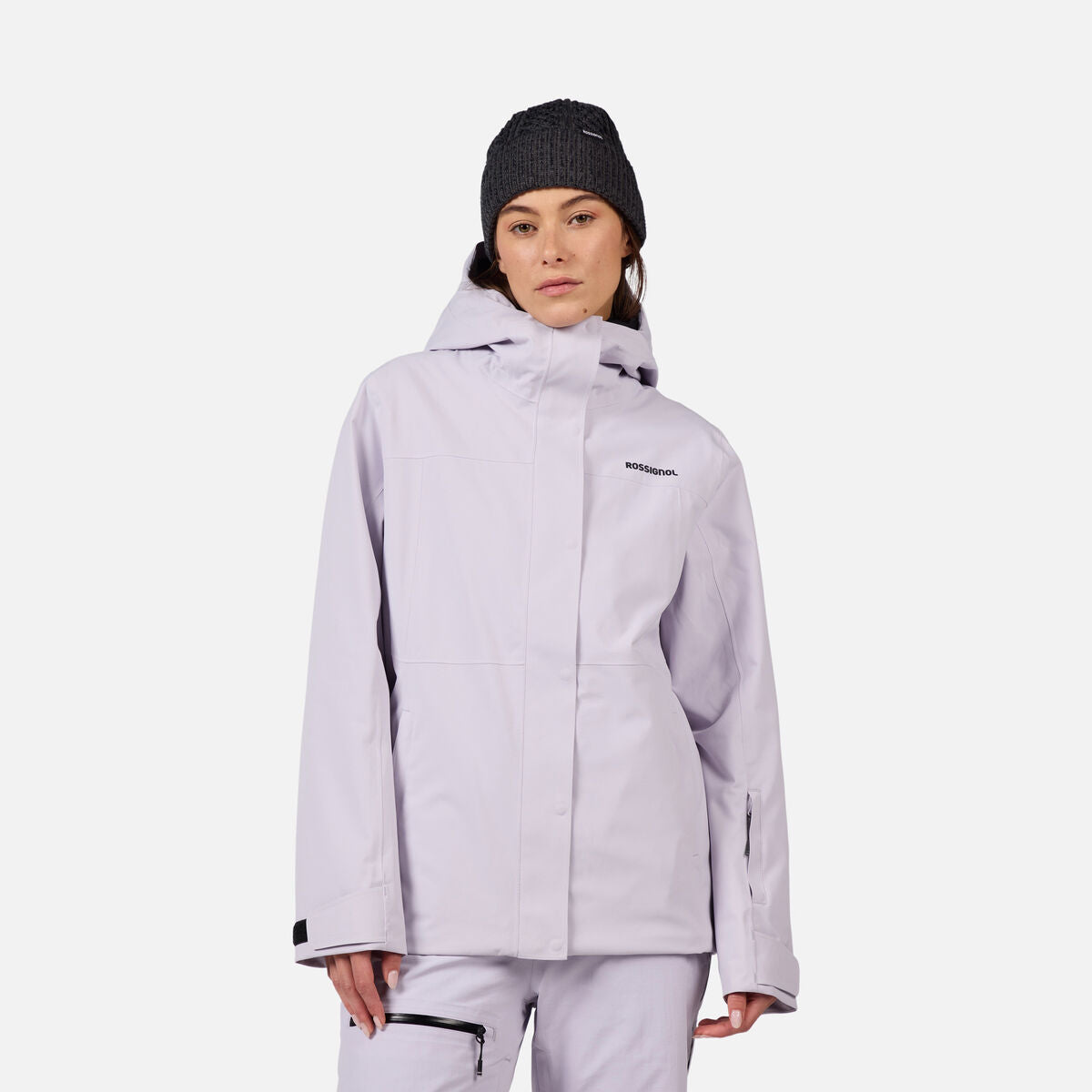 A woman wearing a light purple Rossignol Women's Desafio 2L Shell Ski Jacket that is lightweight, waterproof, breathable, and stretchable.