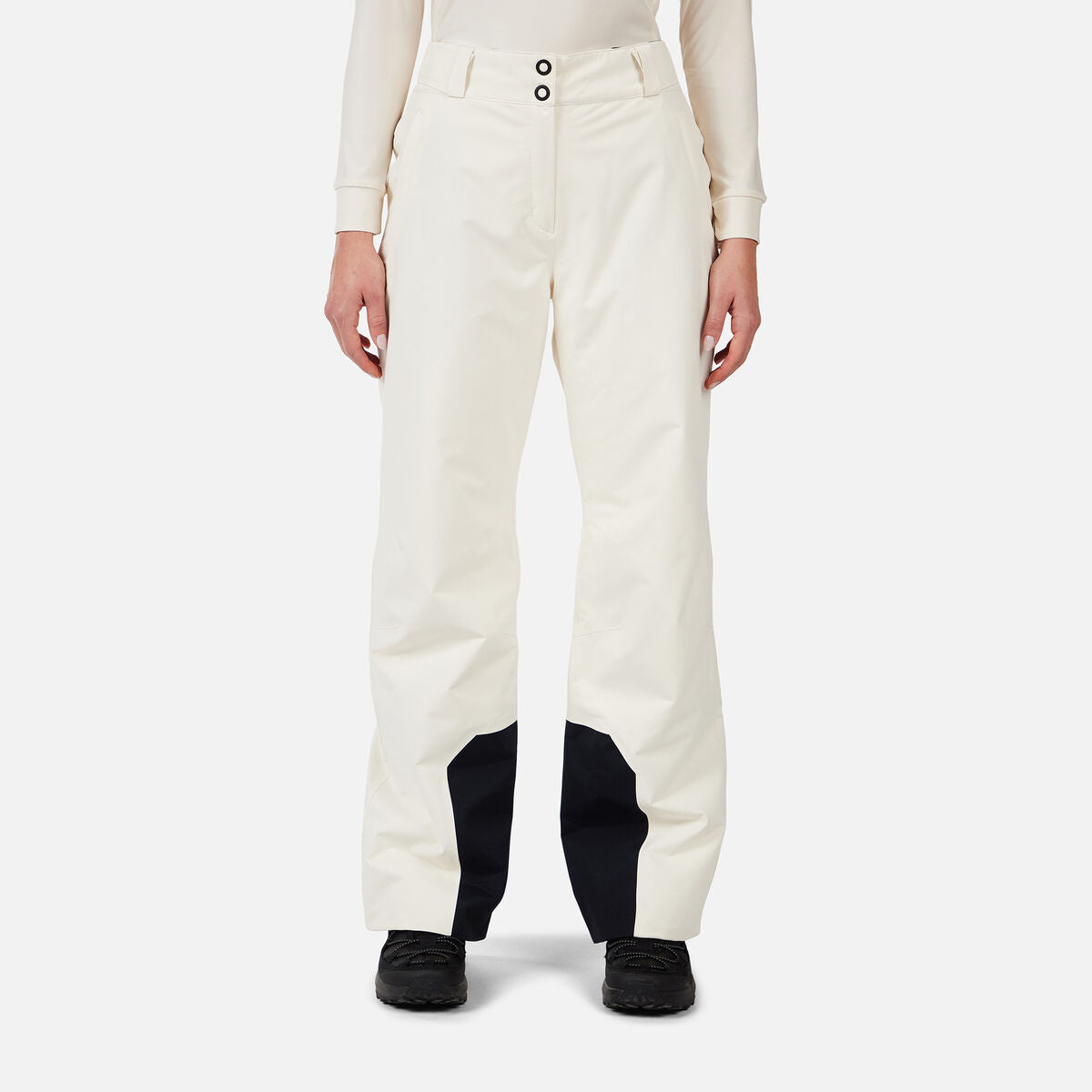 A woman wearing a pair of white Rossignol Women's Insulated Ski Pants that are waterproof, breathable, stretchable, and warm.