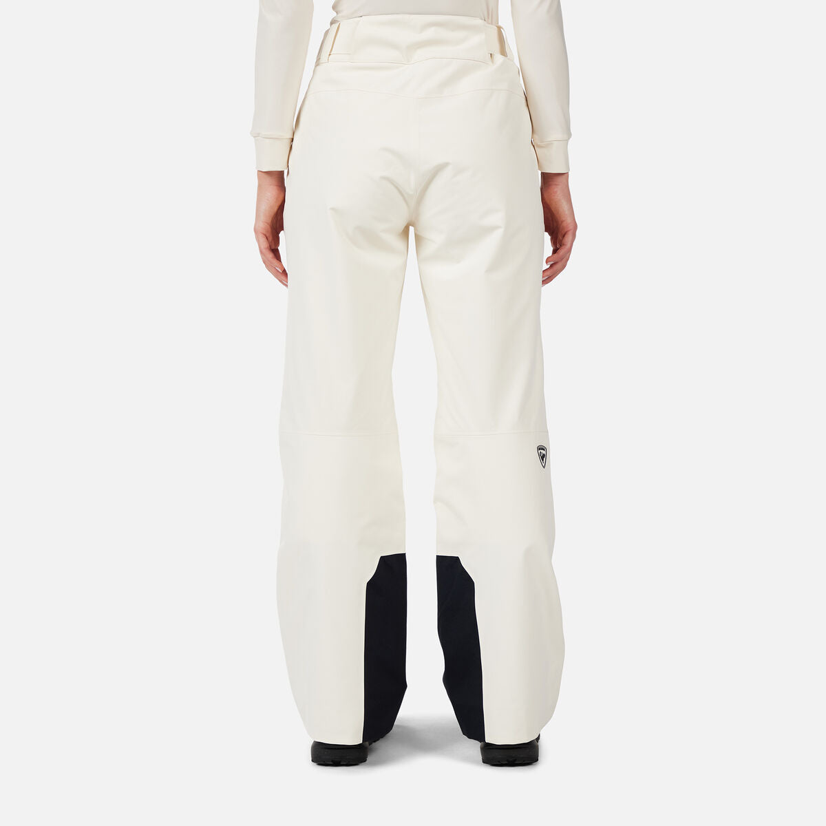 A woman wearing a pair of white Rossignol Women's Insulated Ski Pants that are waterproof, breathable, stretchable, and warm.