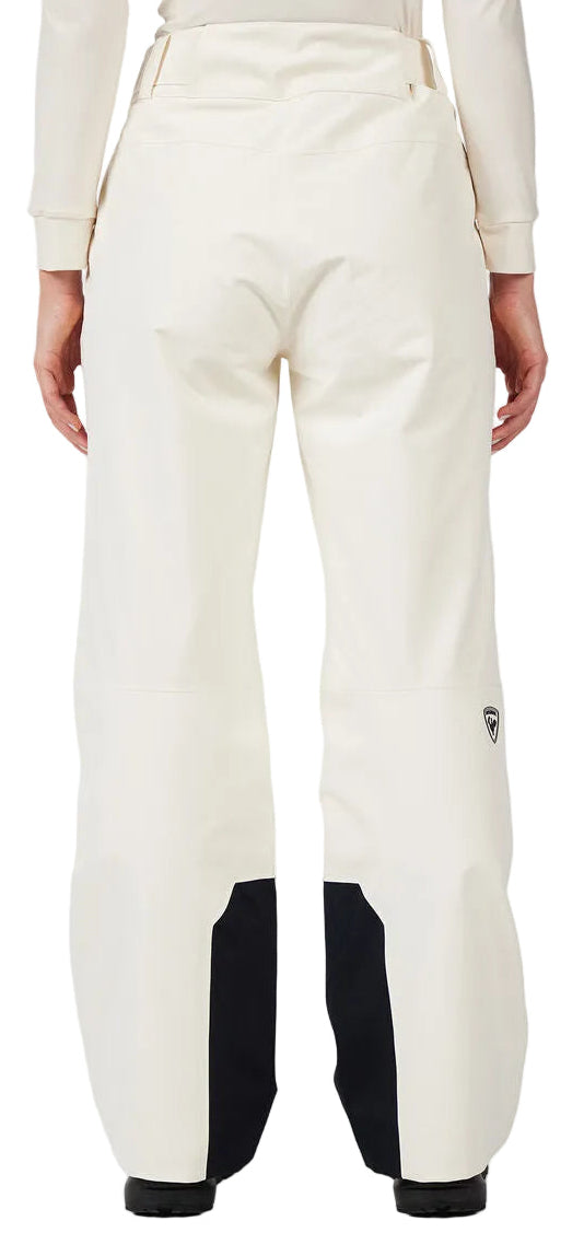 A woman wearing a pair of white Rossignol Women's Insulated Ski Pants that are waterproof, breathable, stretchable, and warm.