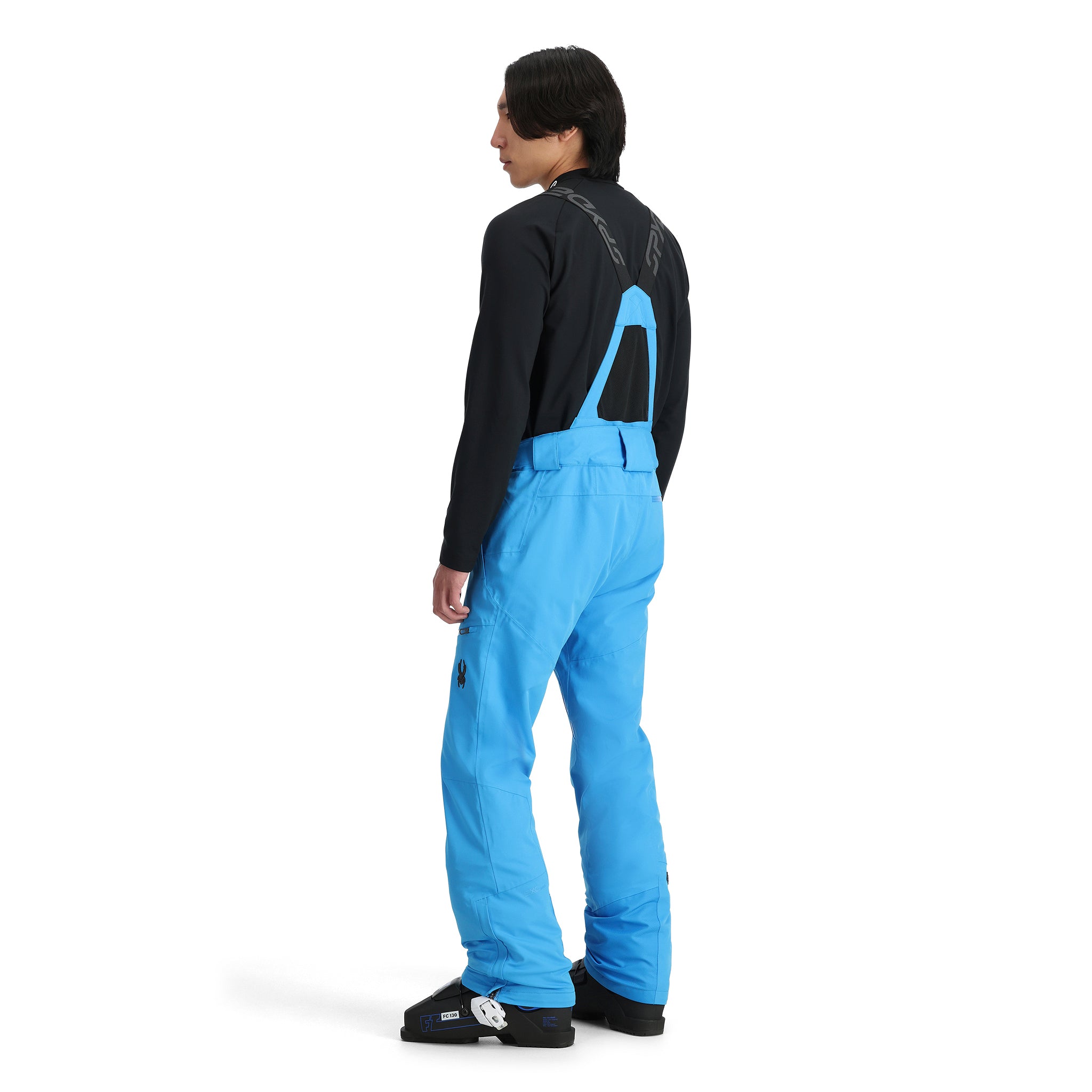 A man wearing a pair of blue Spyder Men's Dare Ski Pants that are waterproof, insulated, breathable, and stretchable.
