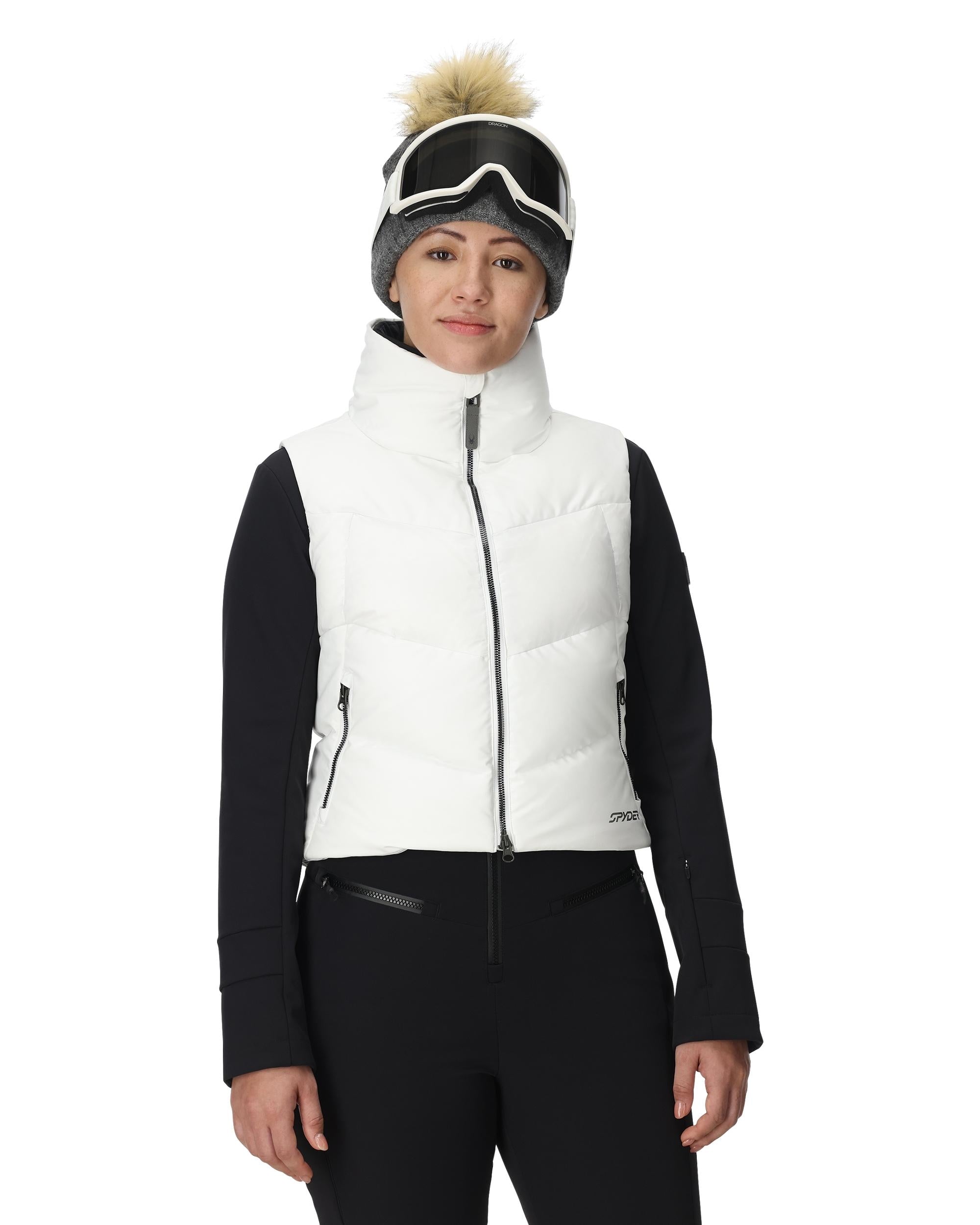 A woman wearing a white Spyder Women's Eastwood Down Vest that is waterproof, breathable, stretchable, and insulated with down.