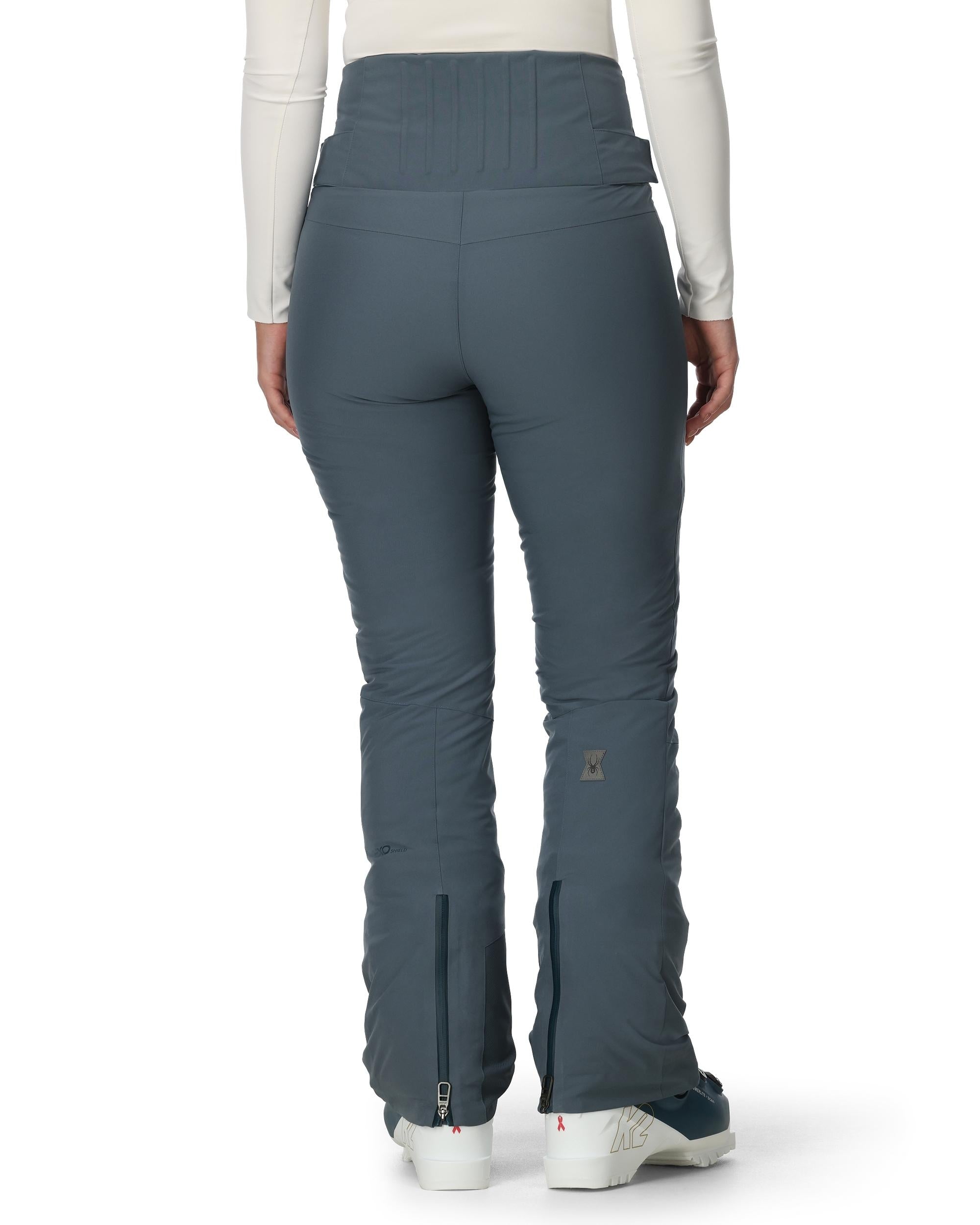 A woman wearing a pair of grey Spyder Women's Fuse Ski Pants that are waterproof, breathable, stretchable, and warm.