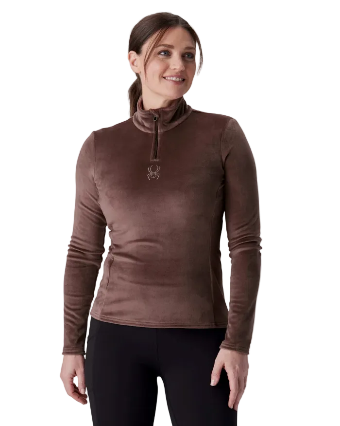 A woman wearing a Spyder Women’s Shimmer Bug 1/2 Zip Sweater featuring stretch velour fleece knit, YKK® reverse coil center front zipper, T-neck collar, and jeweled crystal logo.