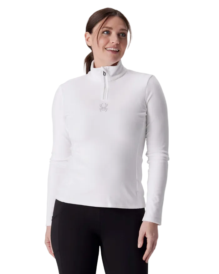 A woman wearing a Spyder Women’s Shimmer Bug 1/2 Zip Sweater featuring stretch velour fleece knit, YKK® reverse coil center front zipper, T-neck collar, and jeweled crystal logo.