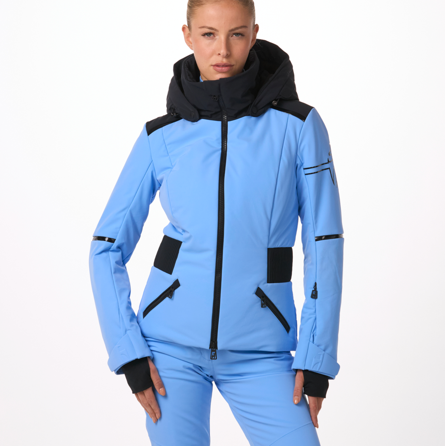 A woman wearing a blue and black Toni Sailer Women's Martha Ski Jacket that is made from premium fabrics and insulation that is waterproof, breathable, stretchable, and insulated.