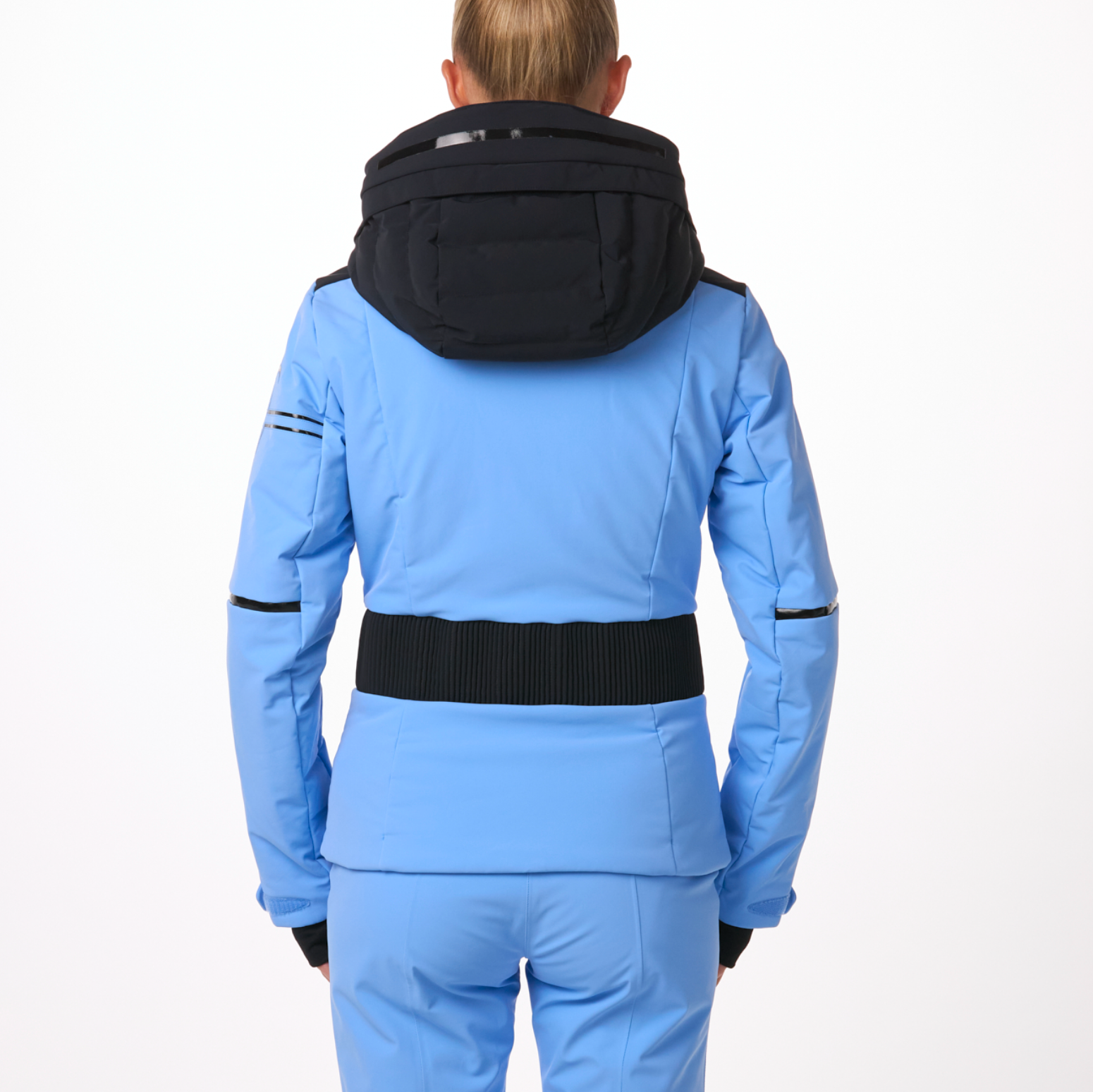A woman wearing a blue and black Toni Sailer Women's Martha Ski Jacket that is made from premium fabrics and insulation that is waterproof, breathable, stretchable, and insulated.