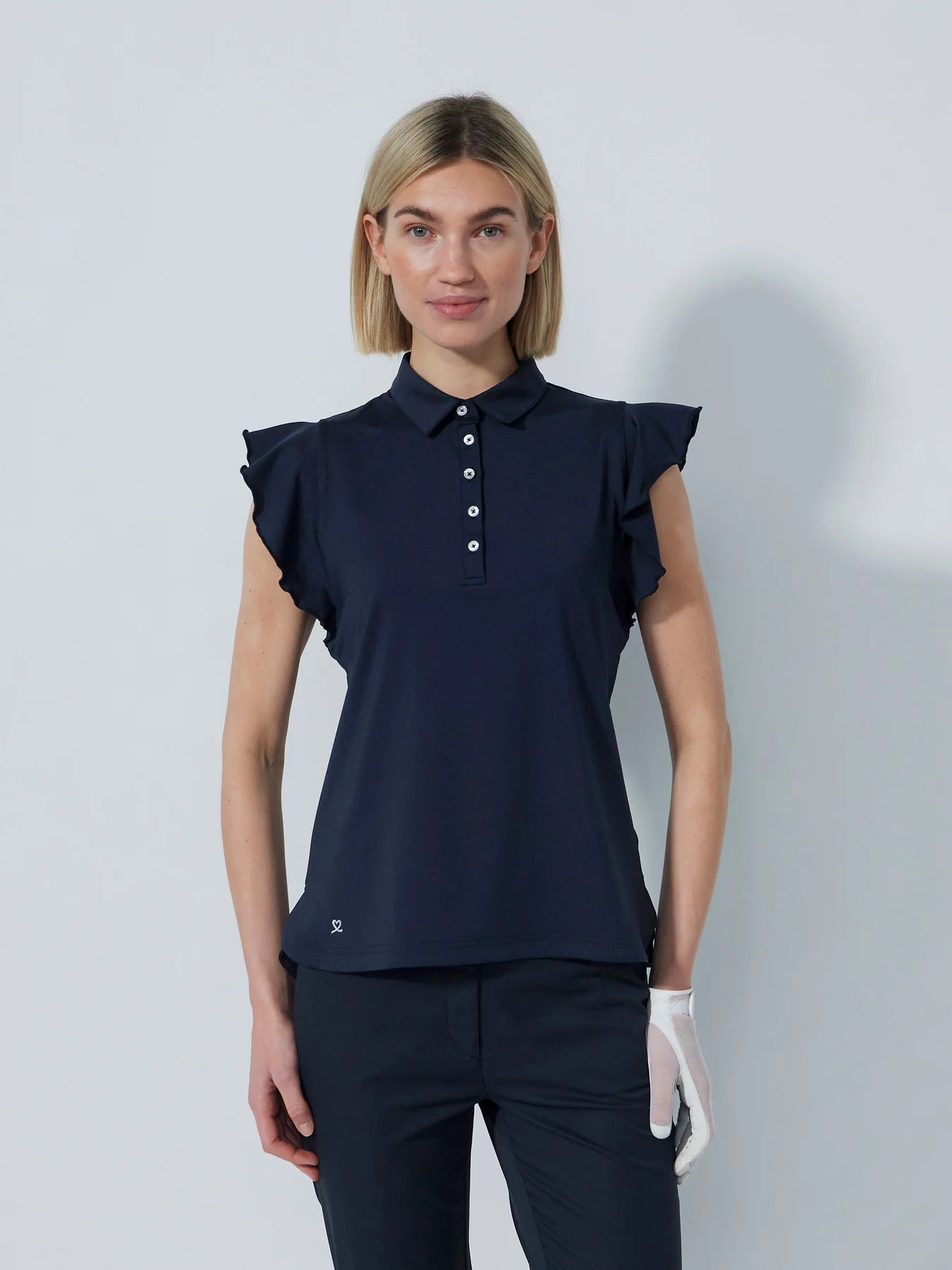 A woman wearing a navy Daily Sports Women's Luxe sleeveless polo shirt with ruffled cap sleeves and a collar.