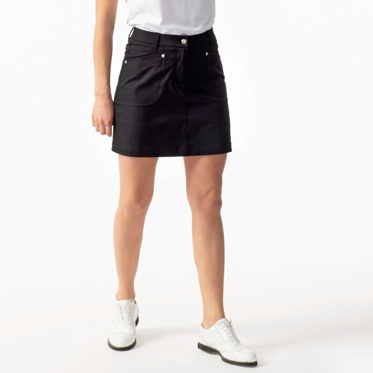 A woman wearing a black Daily Sports Women's Lyric 18" Golf Skort on a white background
