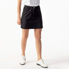 A woman wearing a black Daily Sports Women's Lyric 18" Golf Skort on a white background