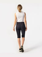 A back-view of a woman wearing a pair of black Daily Sports Women's Lyric City Shorts on a white background