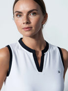 A woman wearing a white Daily Sports Women's Massy Sleeveless Polo Shirt on a white background