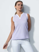 A woman wearing a purple Daily Sports Women's Massy Sleeveless Polo Shirt on a white background