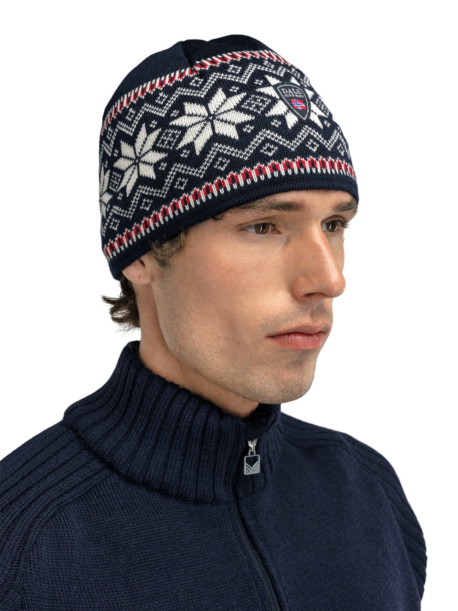 A man wearing a black Dale of Norway Garmisch Hat with a white geometric snowflake pattern that is made from 100% Merino Wool.