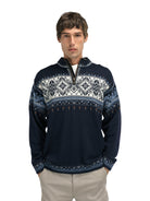 A man wearing a navy Dale of Norway Blyfjell Men's Sweater that is made in Norway from luxurious Norweigan merino wool and features a geometric snowflake pattern.