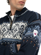 A close-up of a man wearing a navy Dale of Norway Blyfjell Men's Sweater that is made in Norway from luxurious Norweigan merino wool and features a geometric snowflake pattern.