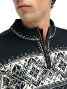 A close-up of a man wearing a navy Dale of Norway Blyfjell Men's Sweater that is made in Norway from luxurious Norweigan merino wool and features a geometric snowflake pattern.