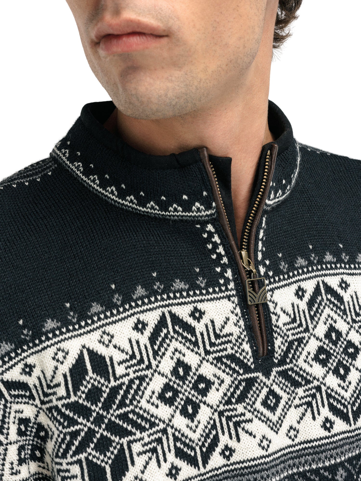 A close-up of a man wearing a navy Dale of Norway Blyfjell Men's Sweater that is made in Norway from luxurious Norweigan merino wool and features a geometric snowflake pattern.