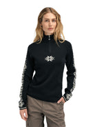 A woman wearing a black Dale of Norway Women’s Geilo turtleneck sweater made in Norway from luxurious Norweigan merino wool.