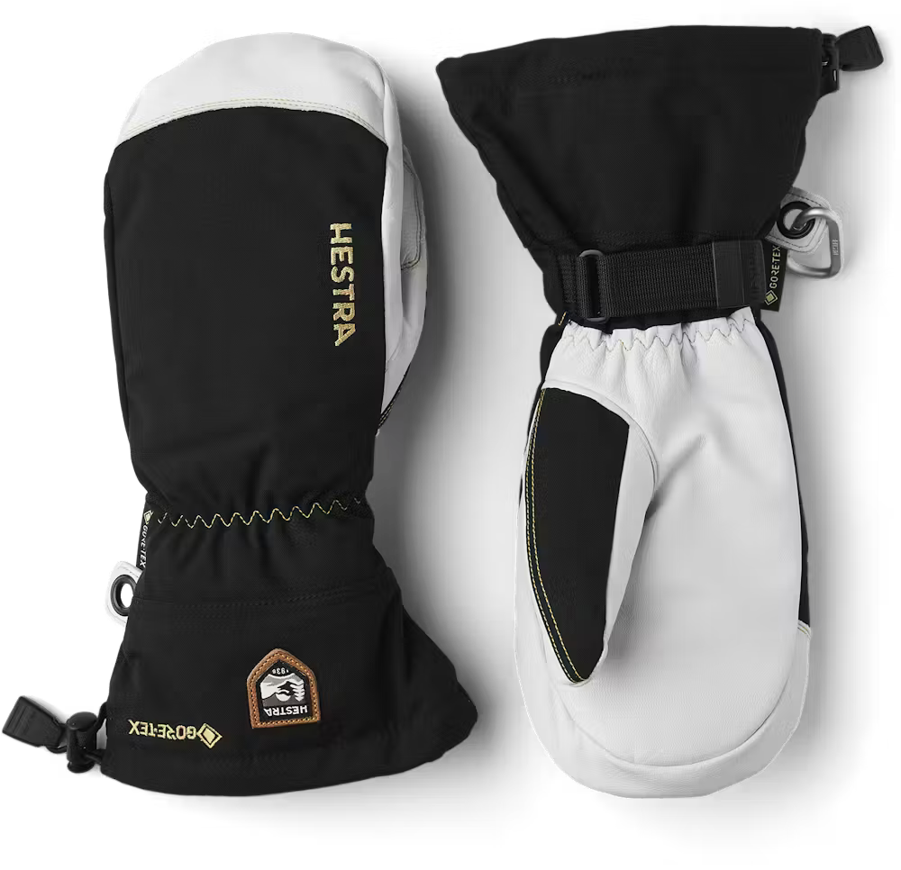 A pair of black and white Hestra Army Leather GORE-TEX Mittens, which are designed to keep your hands warm and dry in harsh winter conditions.