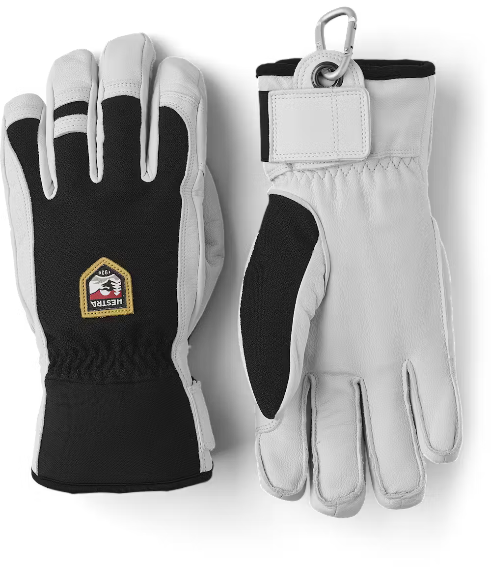 A pair of black and white Hestra Army Leather Patrol gloves that are designed to keep your hands warm and dry in harsh winter conditions.