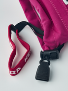 A close-up of the wrist of a pink and white Hestra Junior Army Leather Heli Ski Glove that is made with premium leather.